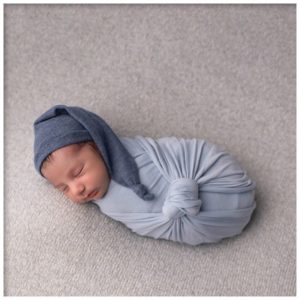 newborn baby boy in a blue wrap and dark blue cap captured by a Southern California Newborn Photographer