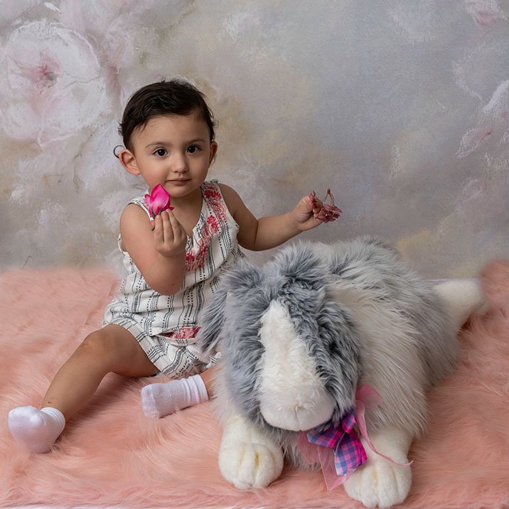 A toddler girl playing on floor with a stuffed animal bunny in Orange County.