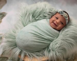 newborn baby girl swaddled in mint green