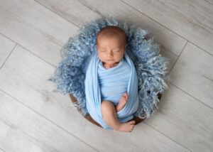 Newborn boy in the East Bay wrapped in blue and sleeping in a bowl.
