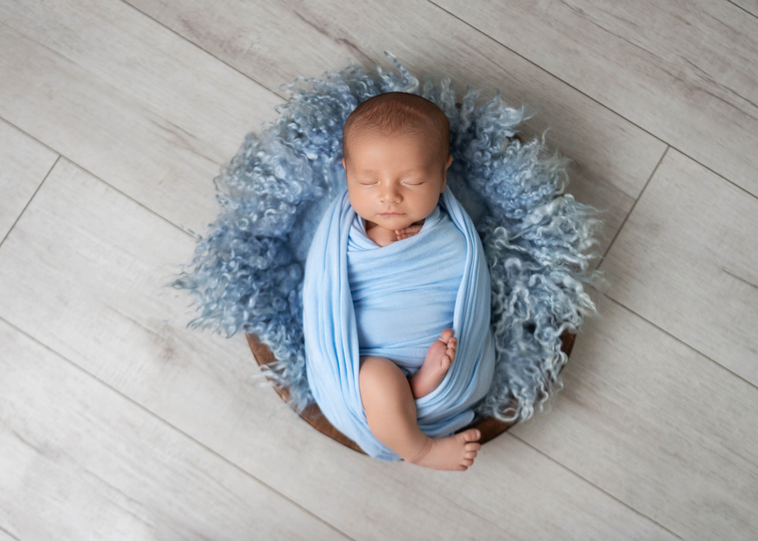 Newborn boy in the East Bay wrapped in blue and sleeping in a bowl.