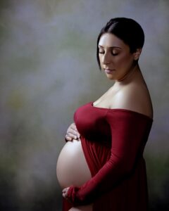 A pregnant woman in the Bay-area wearing a red gown.