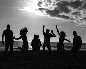 Bay area family jumping up on the beach in a black and white photo.