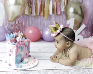 6 month old girl is looking at a birthday cake.