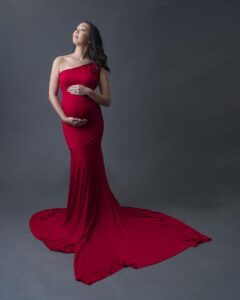 A prenant woman in the Bay Area is wearing a tight red maternity gown.