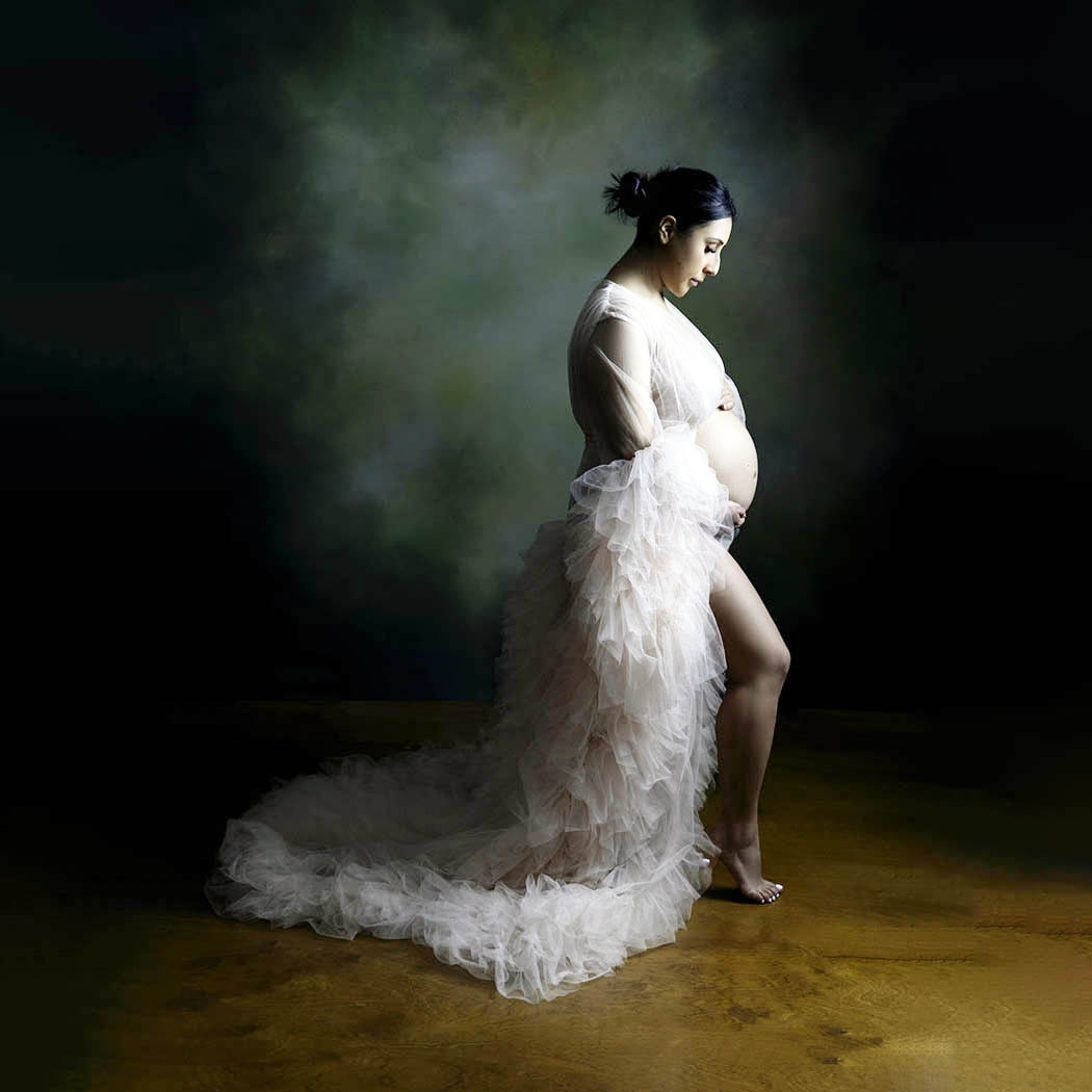 A Bay Area pregnant woman is wearing a pin k gown with ruffles.