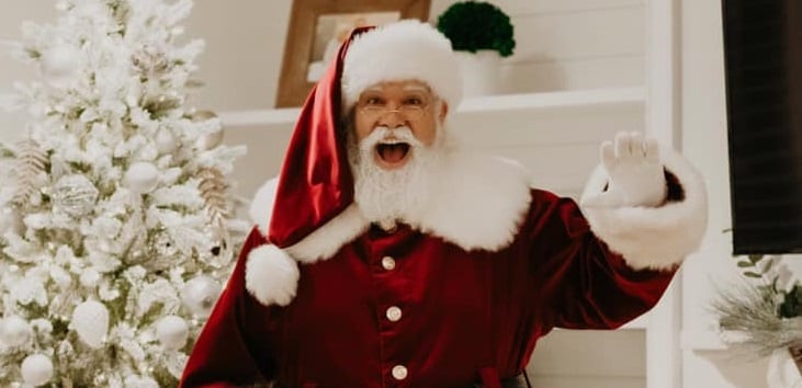 Santa is in the Bay Area in a red suit with a white beard.