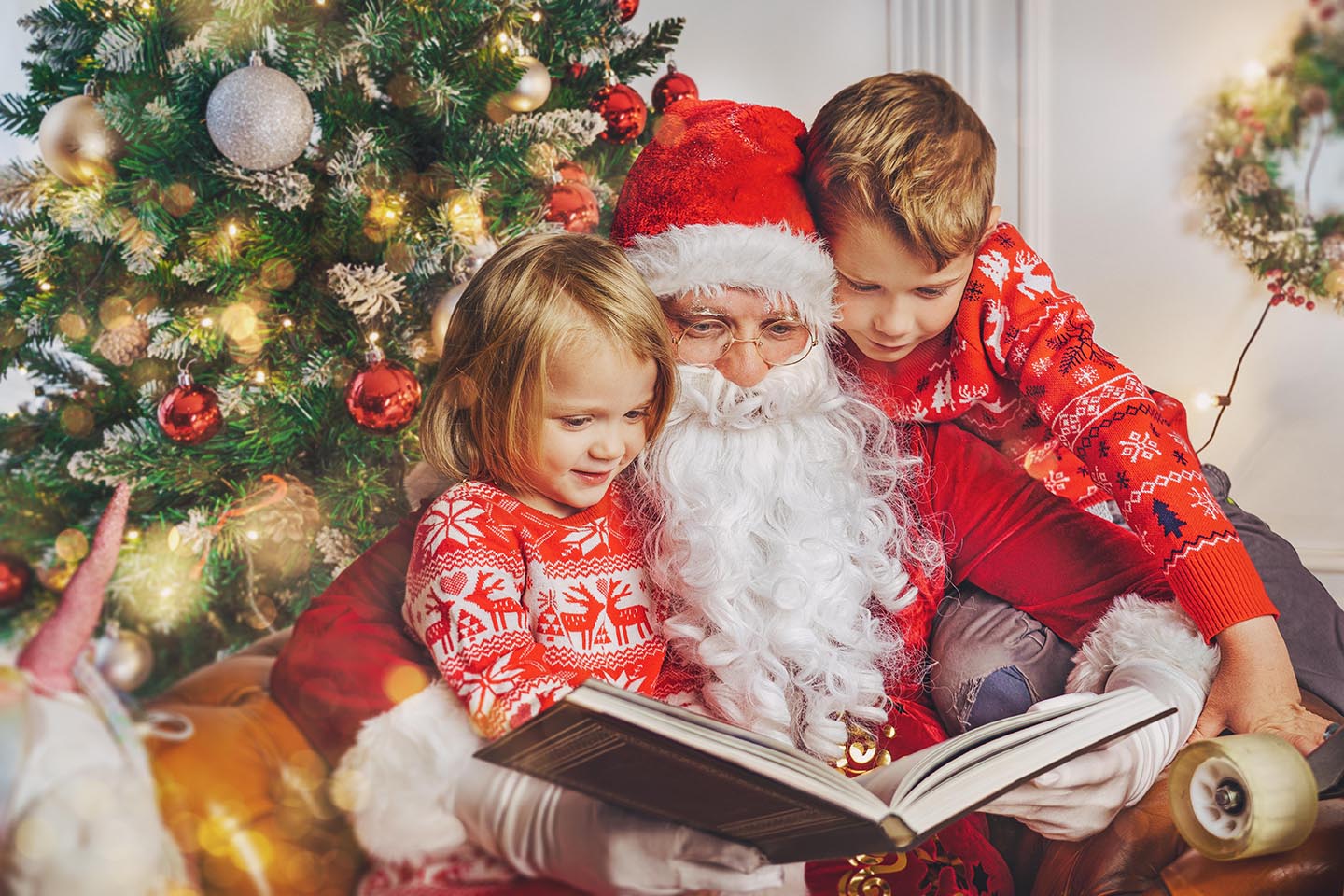 Santa is reading a book to 2 kids in Brentwood