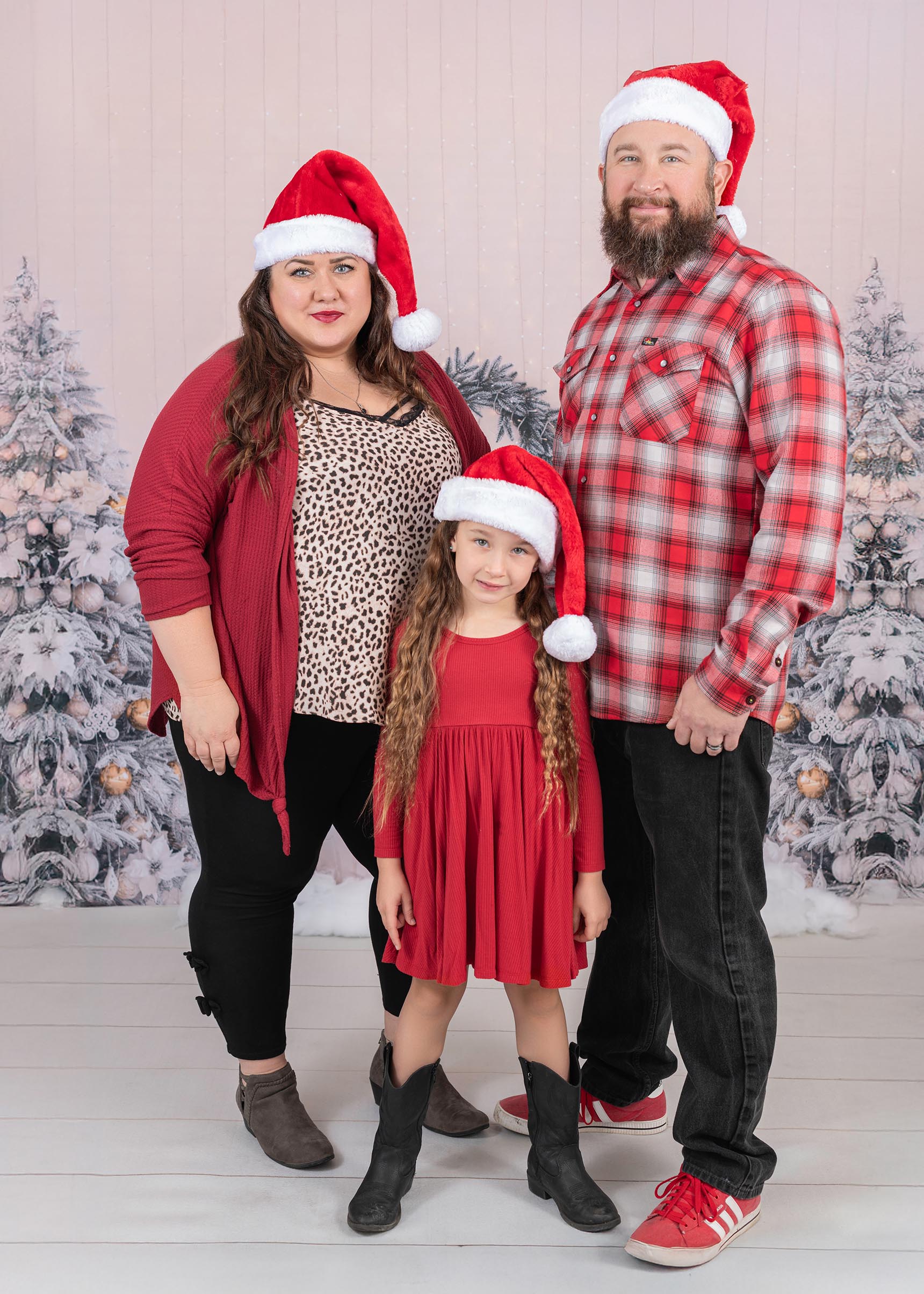 A family of 3 is wearing read and red plaid Christmas outfits.